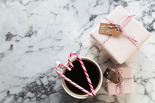 Tasse de café posée à côté de deux paquets cadeaux emballés sur un plan de travail en marbre