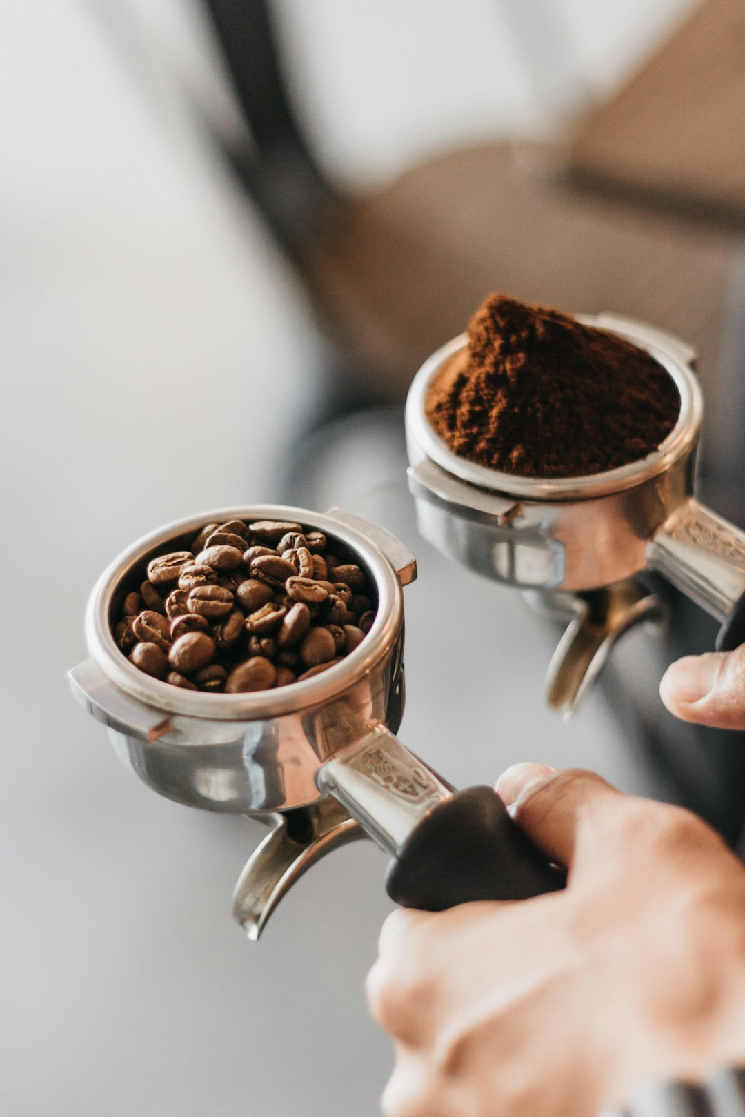 Deux porte-filtres tenus côte à côte, l'un rempli de grains de café entiers, l'autre de café moulu