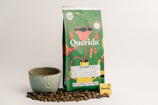 Bag of querida coffee beans with cup and loose beans.